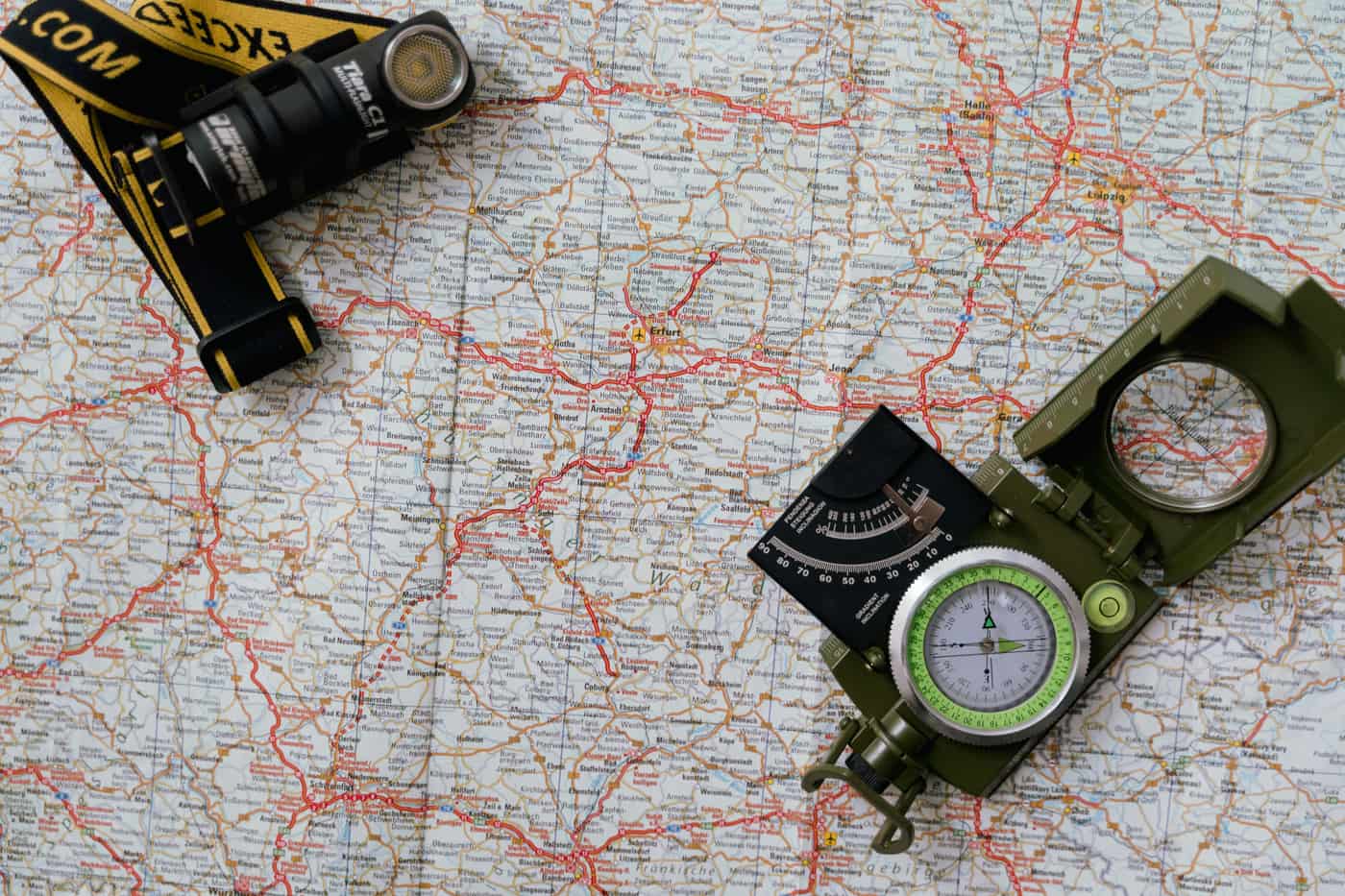 A paper map with a compass and a flashlight laid on it