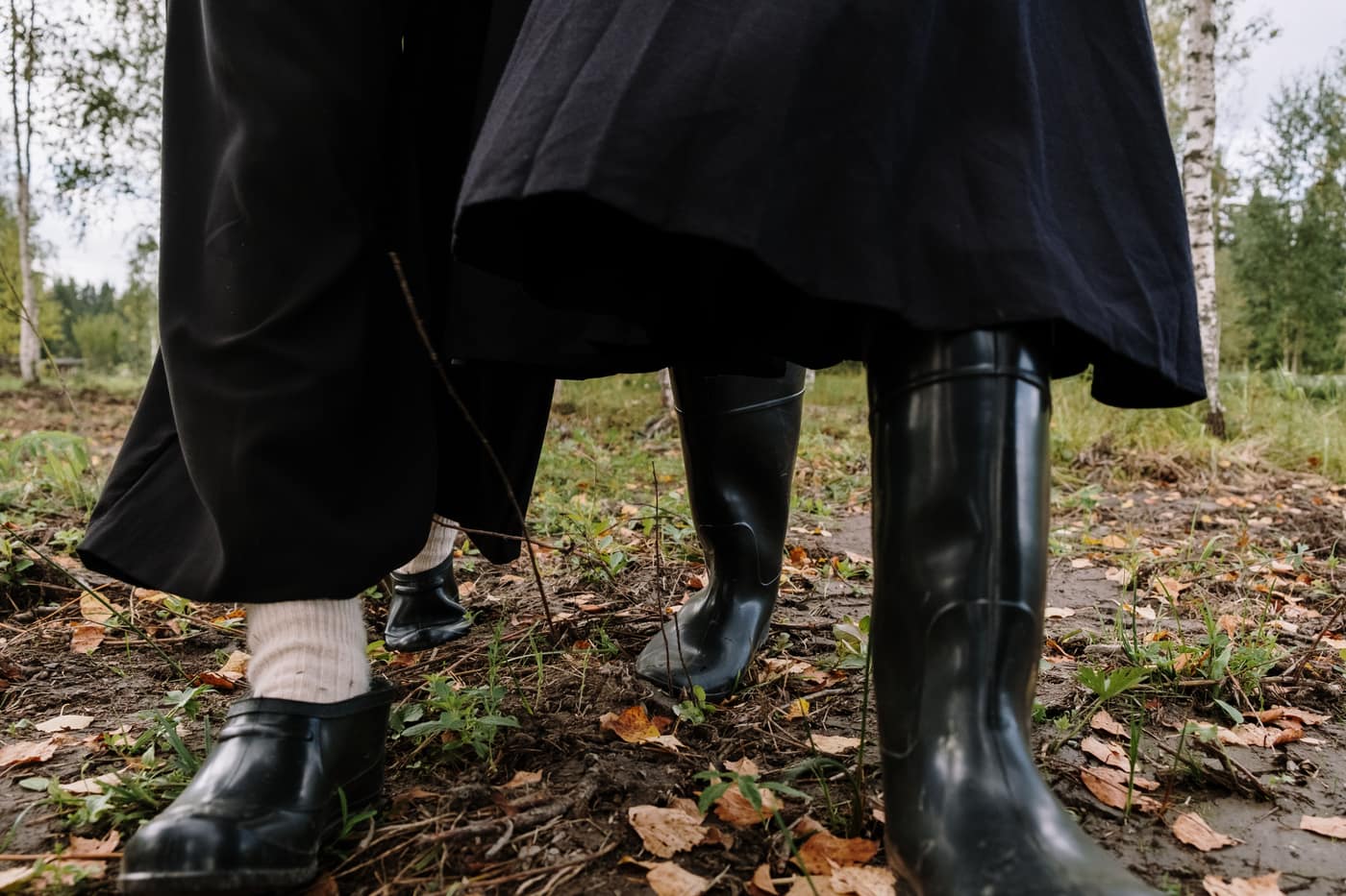 People walking through fallen leaves in rubber boots
