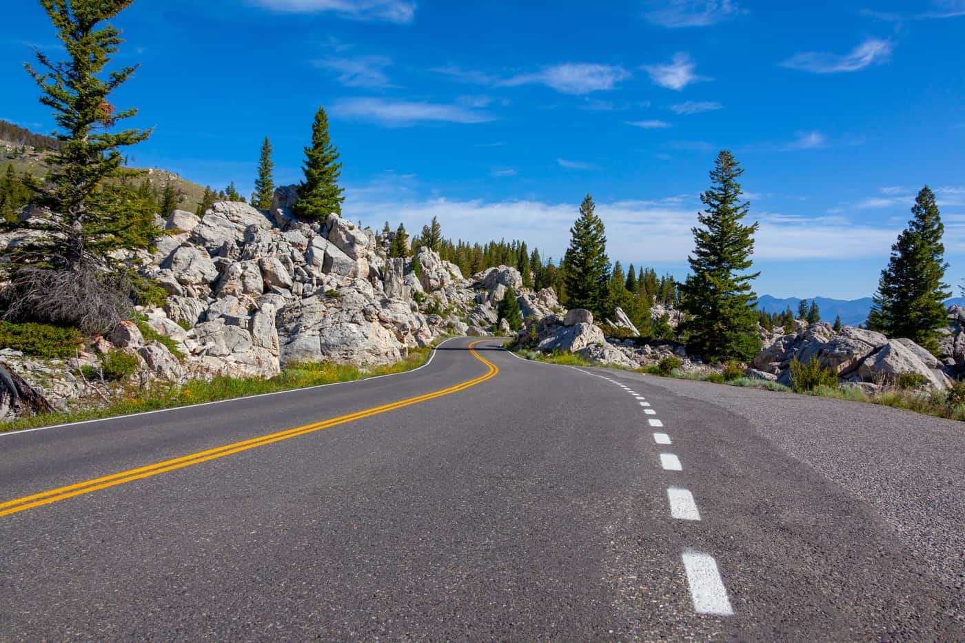 A winding road through trees under a blue sky