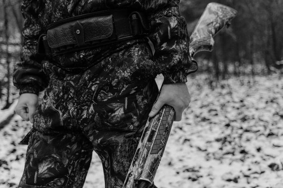 Illustrative stock photo: a black-and-white photo of a hunter in camouflage holding a shotgun