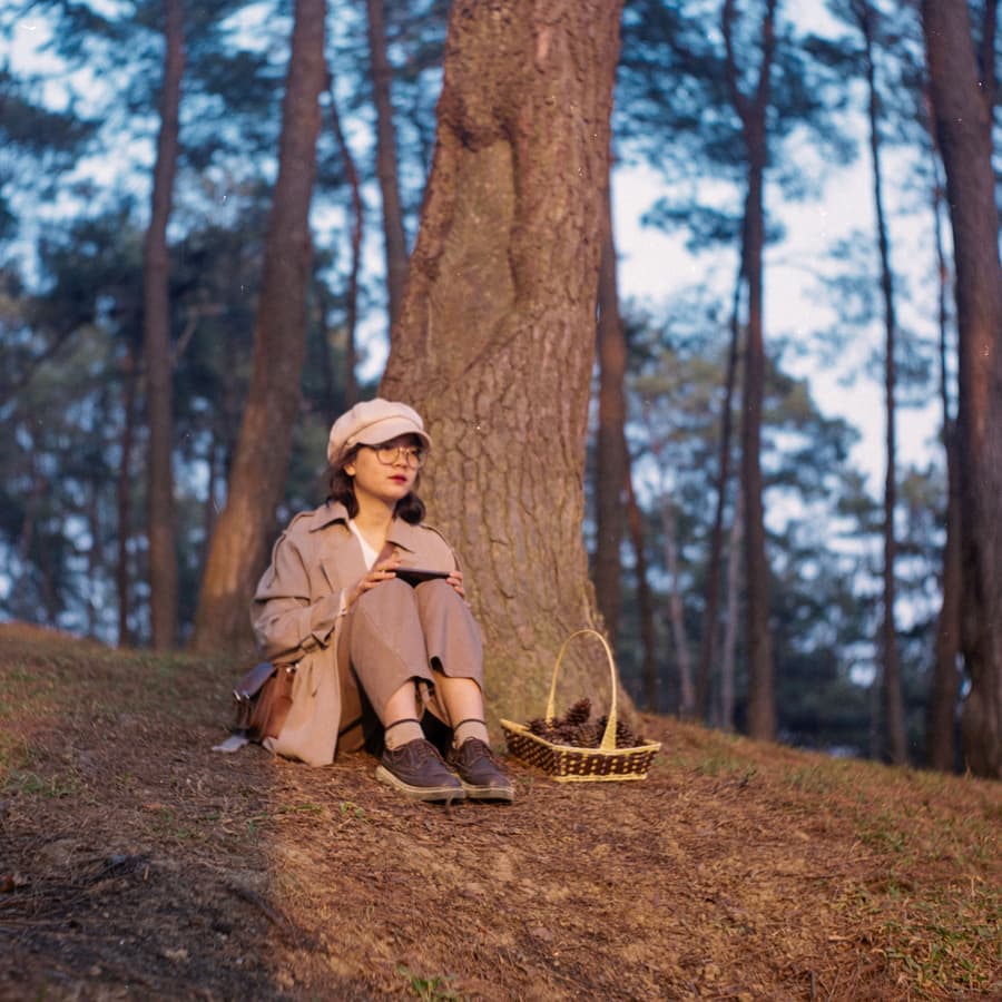 Illustrative stock photo: a person sitting at the base of a tree in the woods